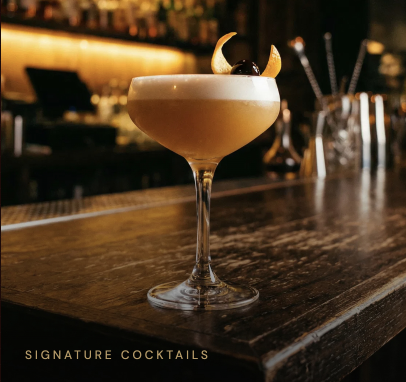 Signature cocktail — amber coupe glass on the Jane bar counter